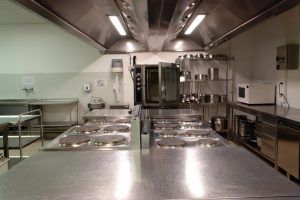 gleaming restaurant kitchen with large hoods suspended over cooktop