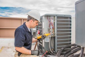 technician repairs ac condenser unit outside apartment