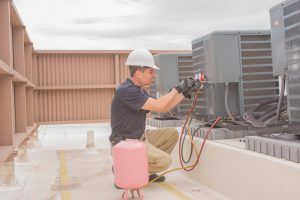 technician repairs ac unit at telecom enclosure